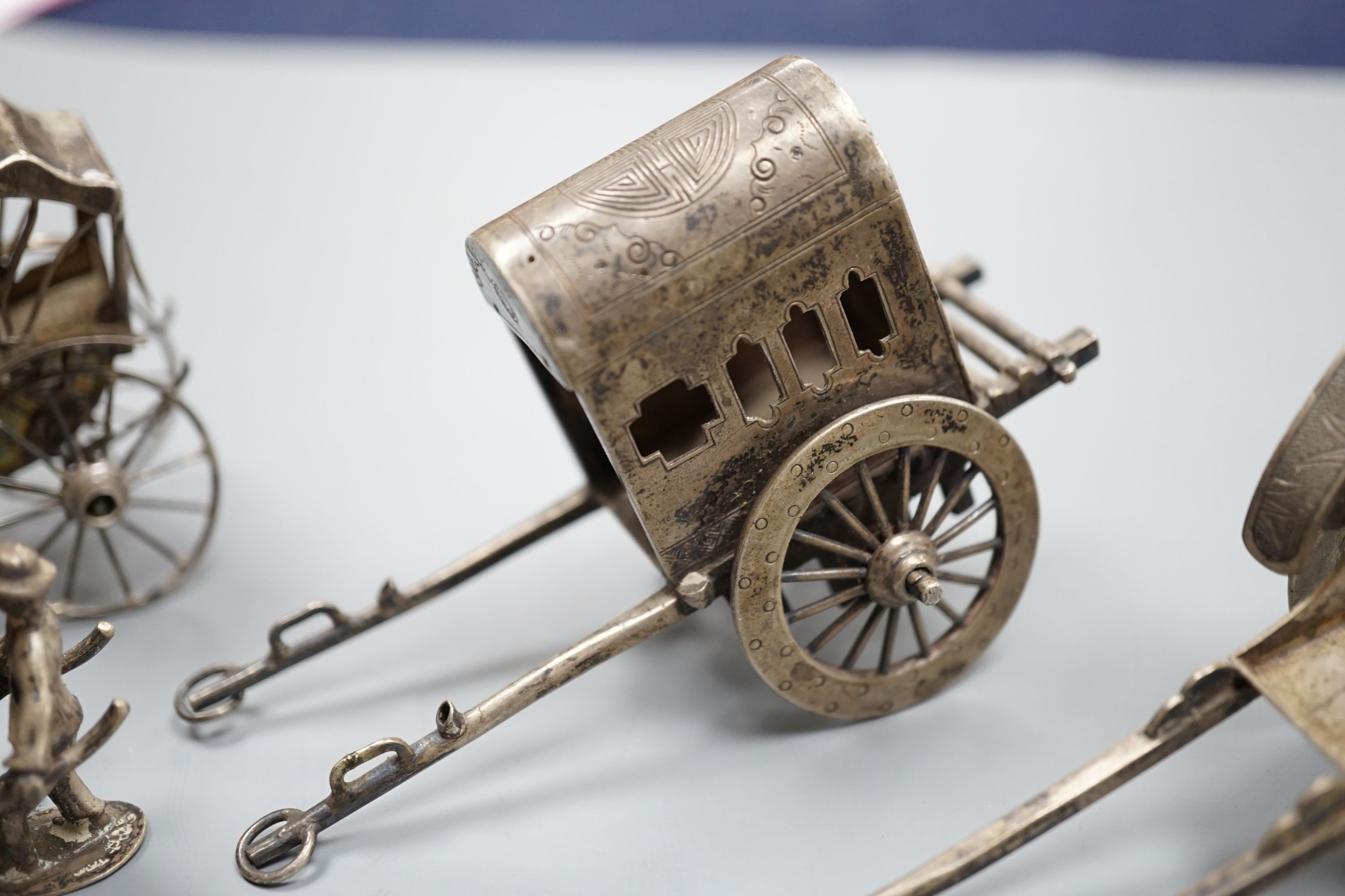 Two early 20th century miniature Chinese white metal models of a figure and rickshaw, by Wang Hing, length approx. 74mm. two other similar Chinese items and and unmarked miniature carriage.